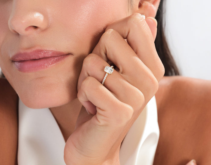Radiant lab grown diamond half pave ring in rose gold worn on the hand held against the cheek