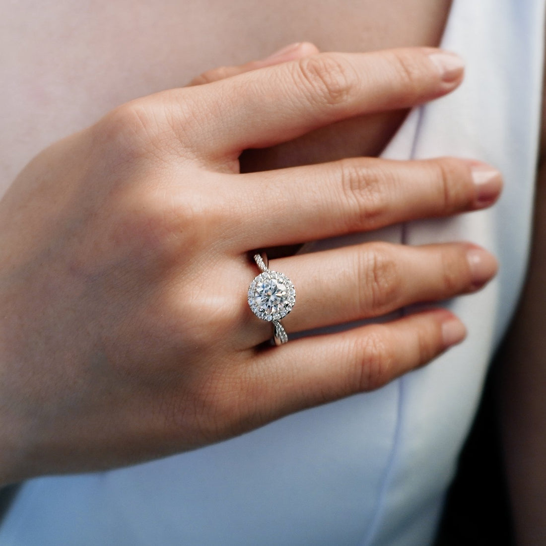 Round brilliant moissanite circular halo engagement ring on a twisted pave shank in white gold