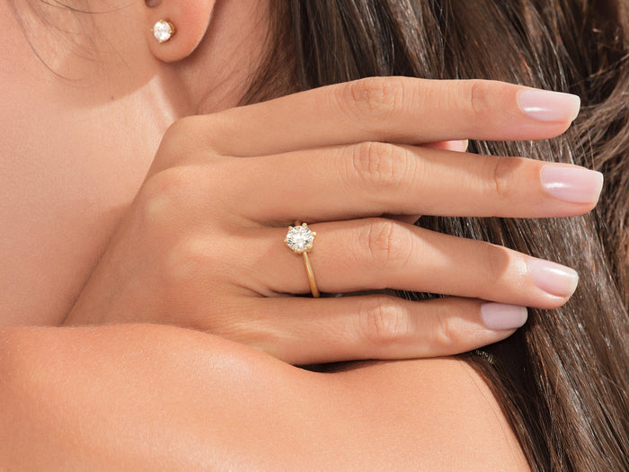 Round moissanite solitaire style hidden halo ring in yellow gold worn on the hand