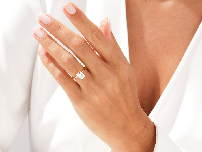 Radiant moissanite knife edge solitaire in yellow gold worn on the hand