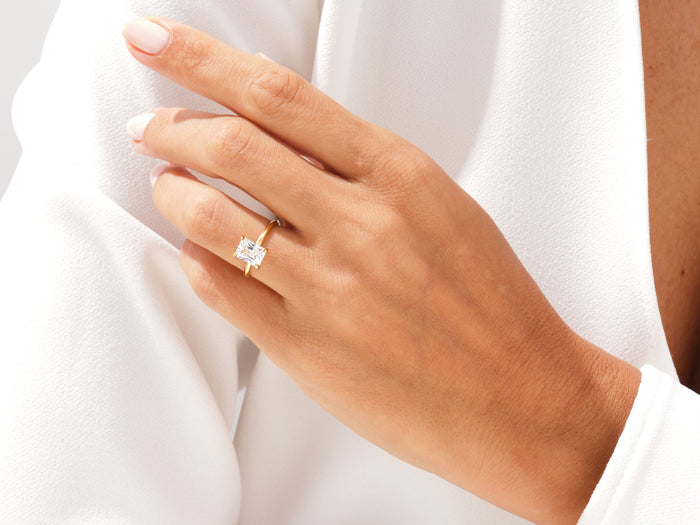 Radiant moissanite four prong ring in yellow gold worn on the ring finger