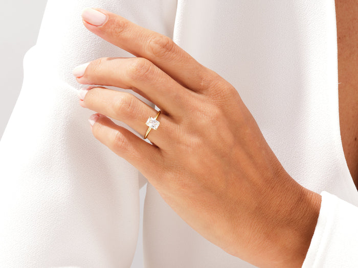 Radiant cut lab grown diamond knife edge ring in yellow gold worn on the hand at the shoulder
