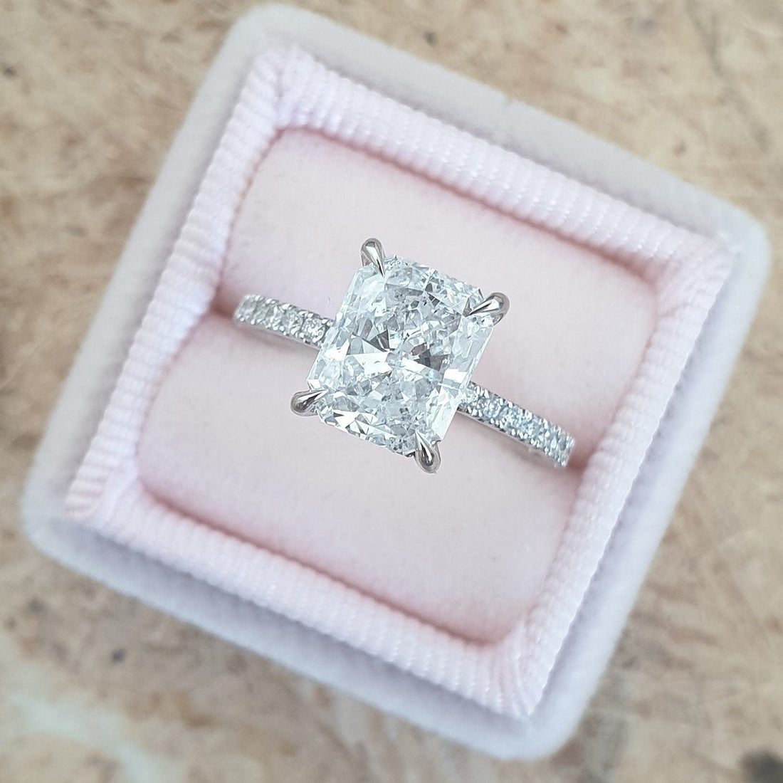 Elongated radiant cut moissanite four claw engagement ring on a micro pave shank in white gold