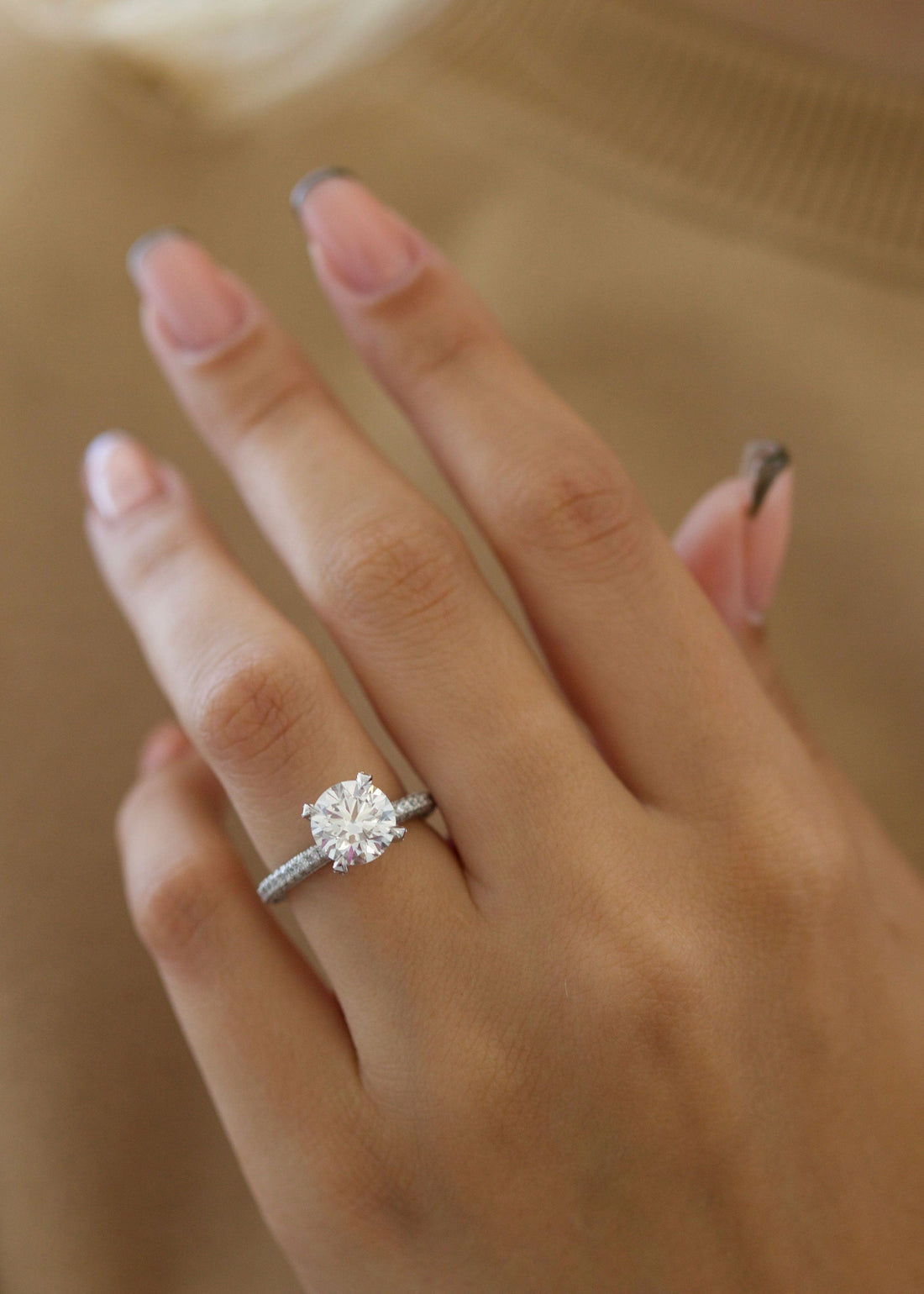Round brilliant moissanite solitaire engagement ring on a pave white gold band