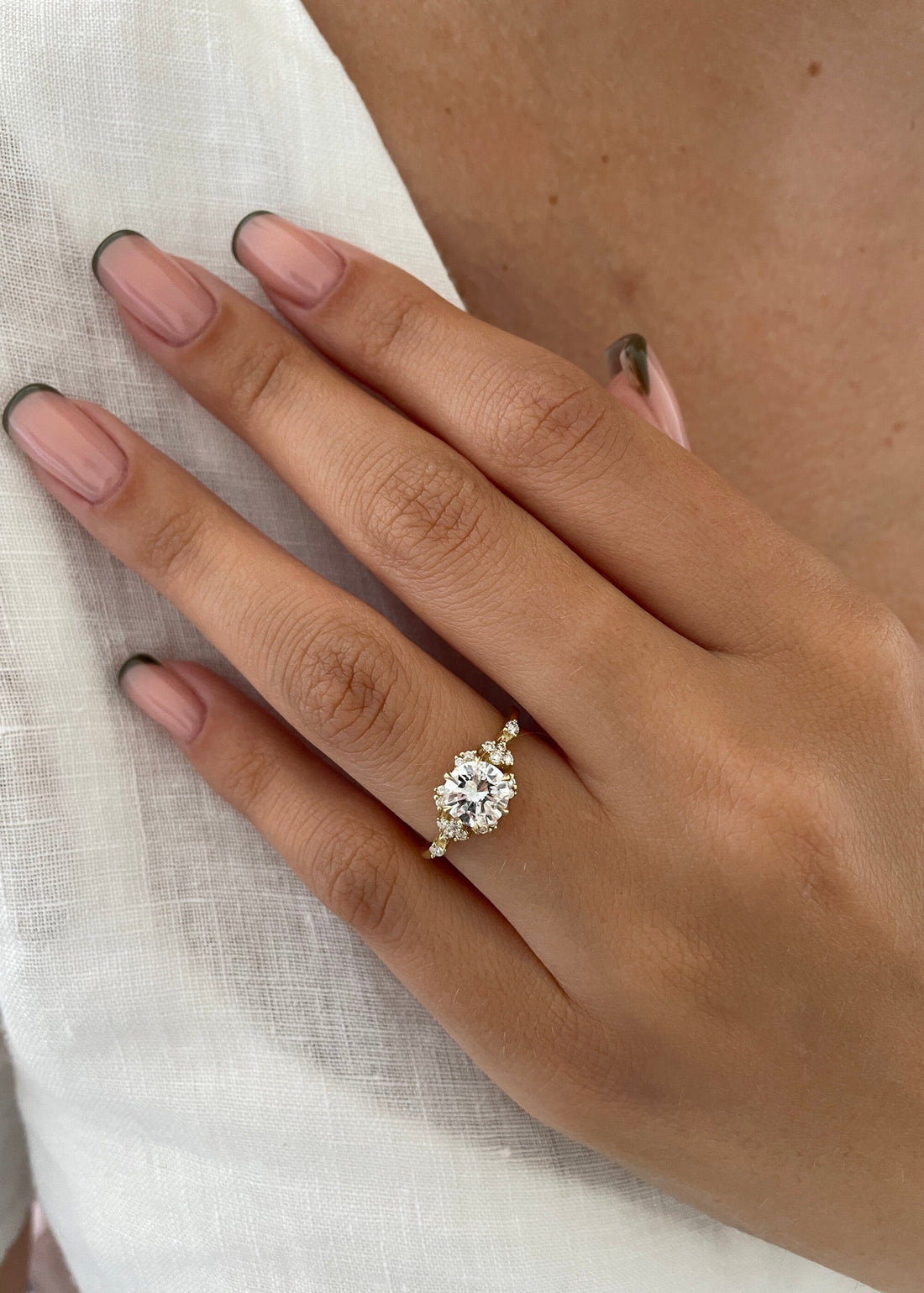 Round brilliant moissanite engagement ring with petal cluster shoulders in yellow gold