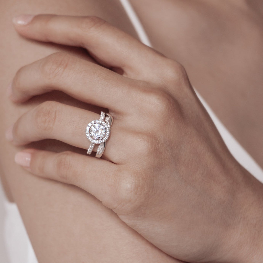 Round brilliant moissanite petite halo engagement ring on a fine pave band in white gold