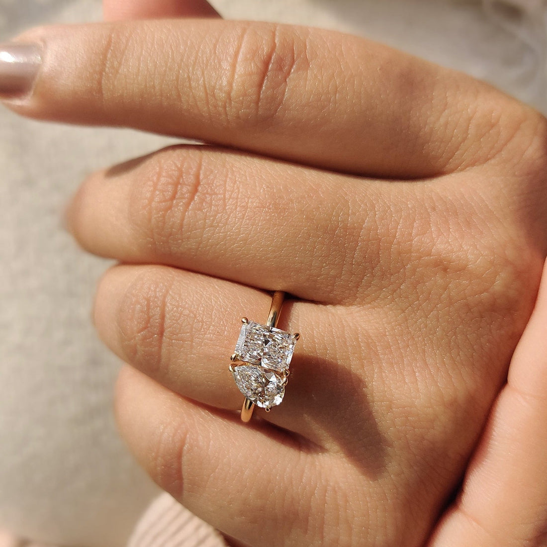 Radiant and pear cut moissanite toi et moi engagement ring on a fine yellow gold band