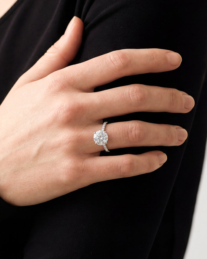 Round lab grown diamond pave band ring in white gold worn on a hand against a black top