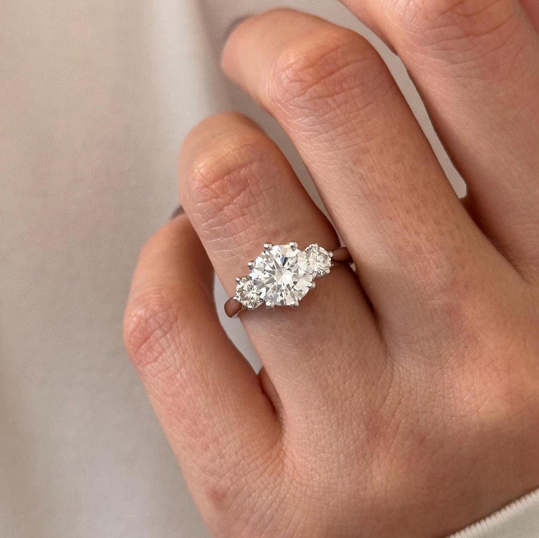 Round cut moissanite three stone engagement ring with round side stones in white gold