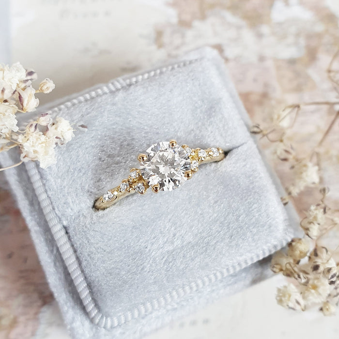 Round brilliant moissanite scattered accent shoulder engagement ring in yellow gold, view 2