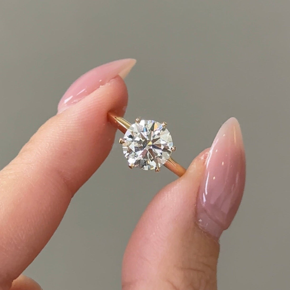 Round cut moissanite six claw solitaire engagement ring on a fine band in yellow gold