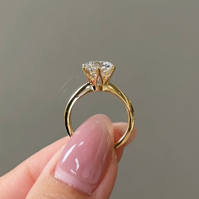 Round cut moissanite six claw solitaire engagement ring on a fine band in yellow gold, view 2