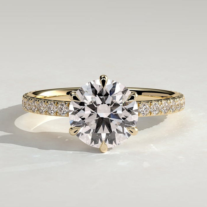 Round brilliant moissanite six claw solitaire engagement ring on a pave yellow gold band
