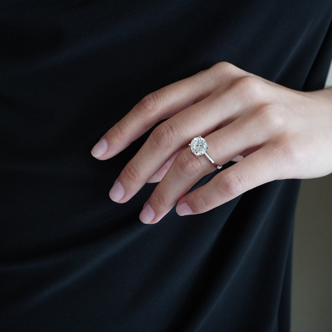 Round brilliant moissanite tall basket solitaire engagement ring on a hairline white gold band