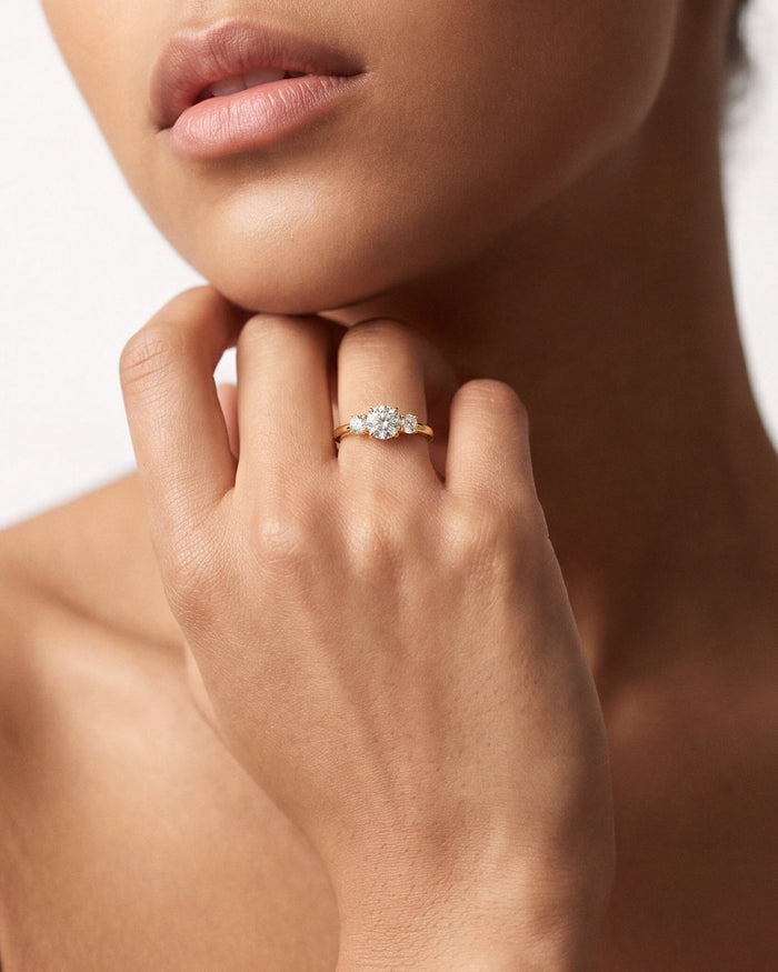 Round lab grown diamond three stone ring worn on the hand held under the chin