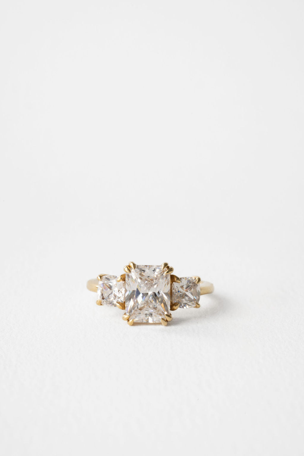 Radiant cut moissanite three stone engagement ring with cushion cut side stones in yellow gold