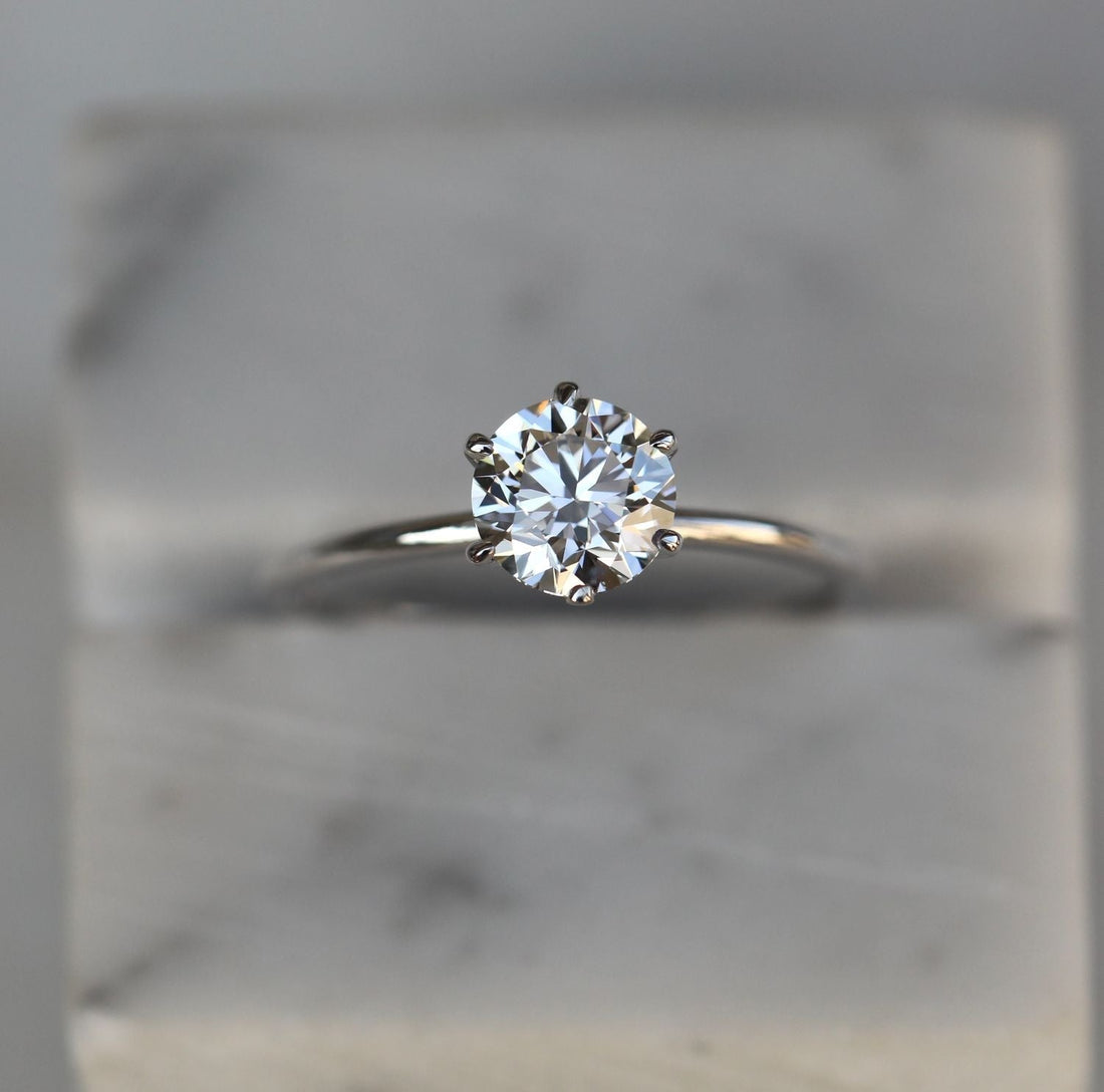 Round brilliant moissanite slim talon claw solitaire engagement ring on a tapered white gold band