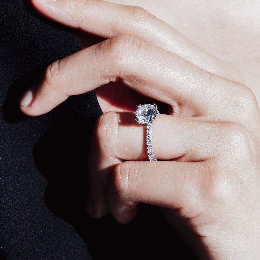 Round brilliant moissanite engagement ring on a triple row pave shank in white gold