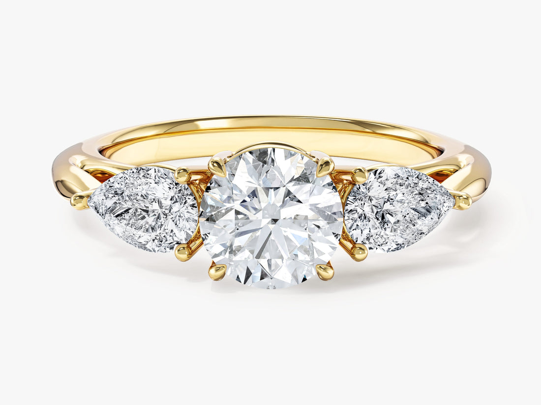 Round moissanite three stone engagement ring with pear side stones in yellow gold, front view