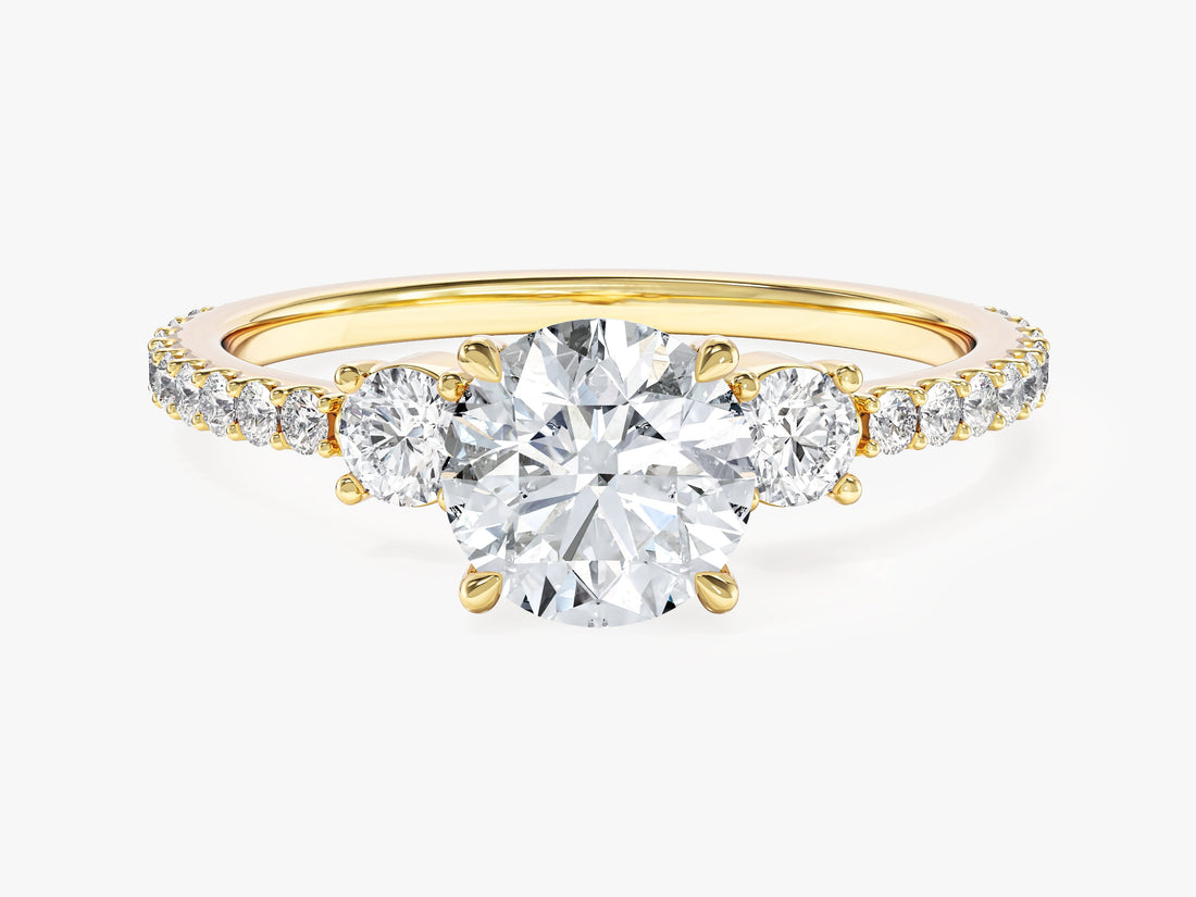 Round moissanite three stone engagement ring with micro pave band in yellow gold, front view