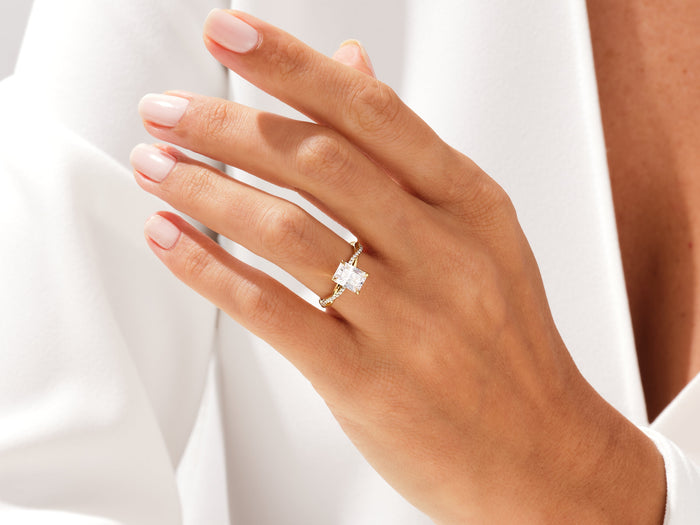 Radiant cut lab grown diamond infinity twist ring in yellow gold worn on a relaxed hand