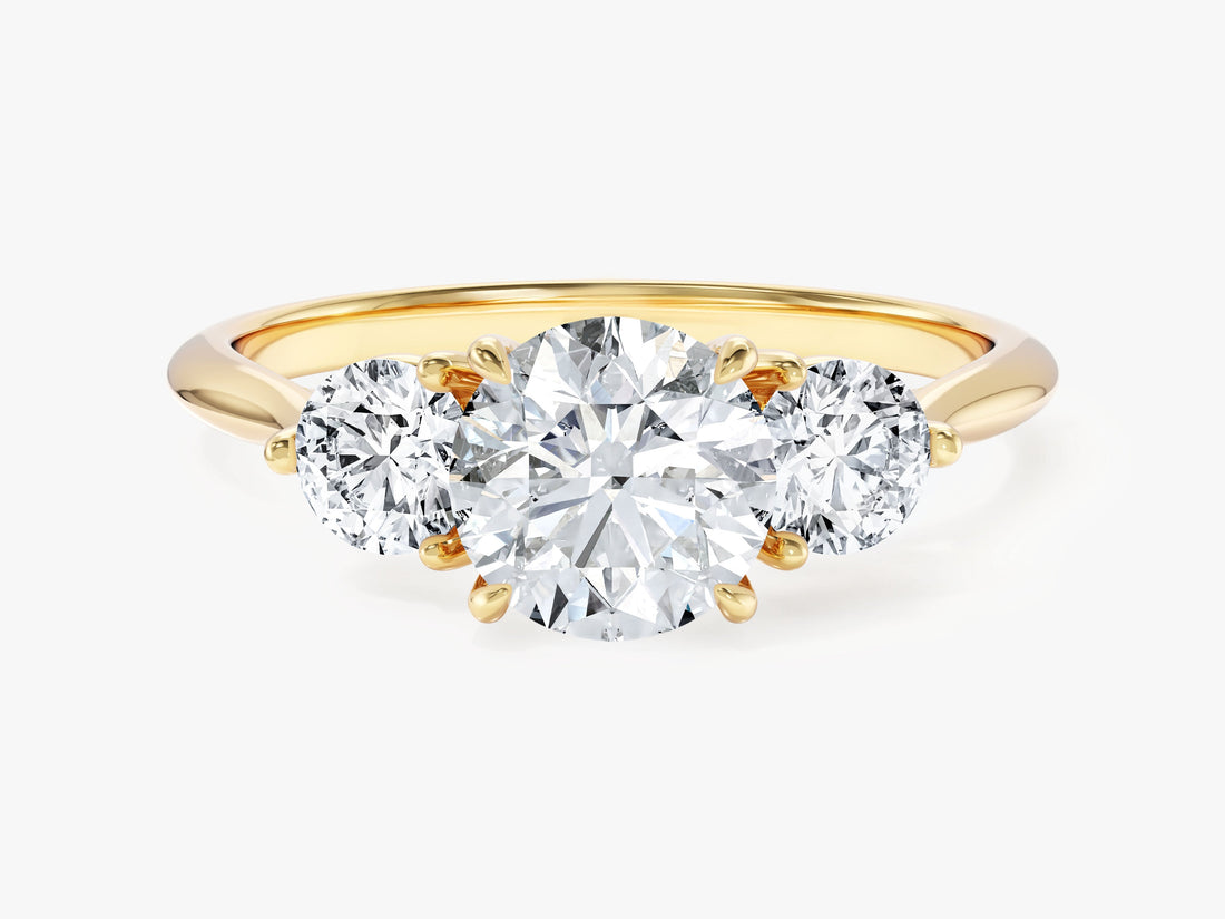 Round moissanite three stone trilogy engagement ring in yellow gold, front view