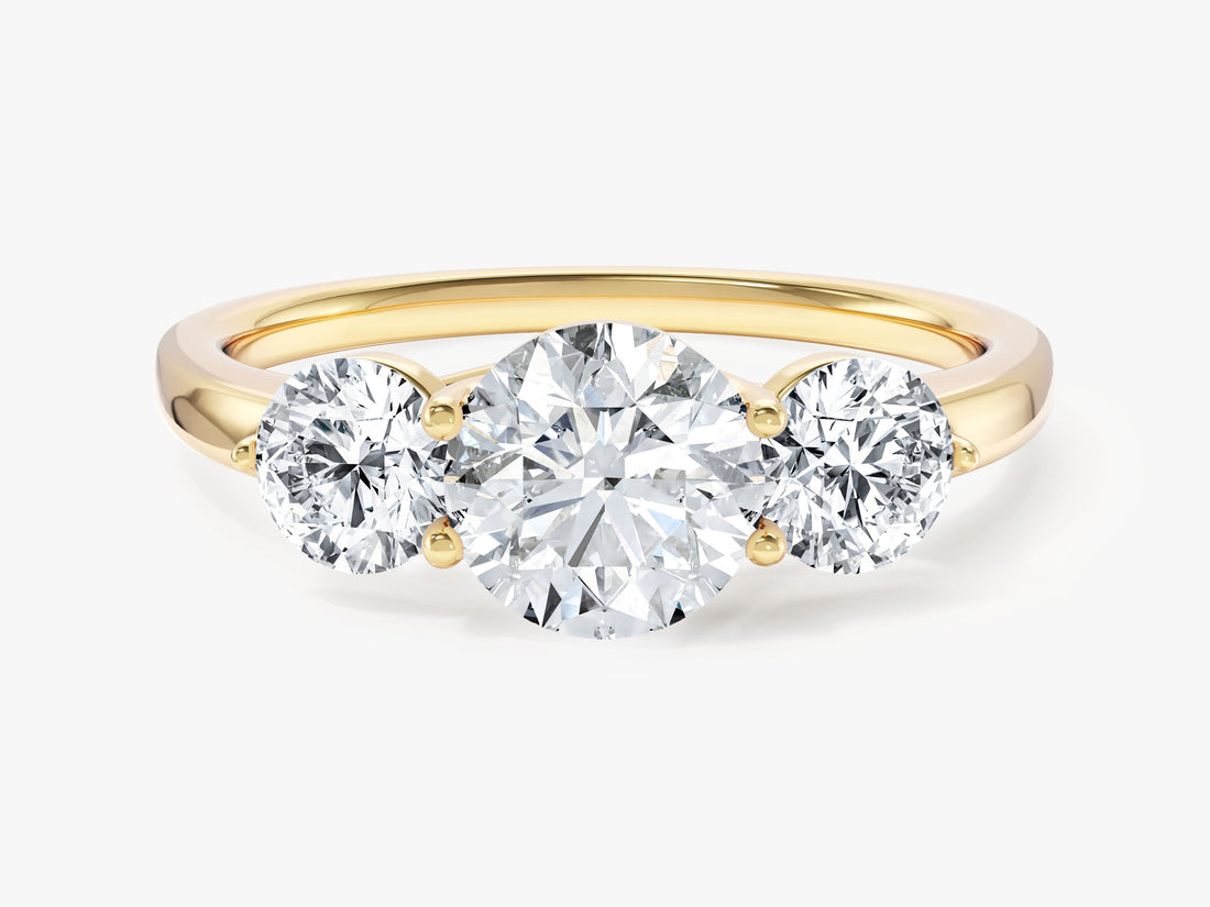 Round brilliant moissanite prong set trio engagement ring in yellow gold, front view