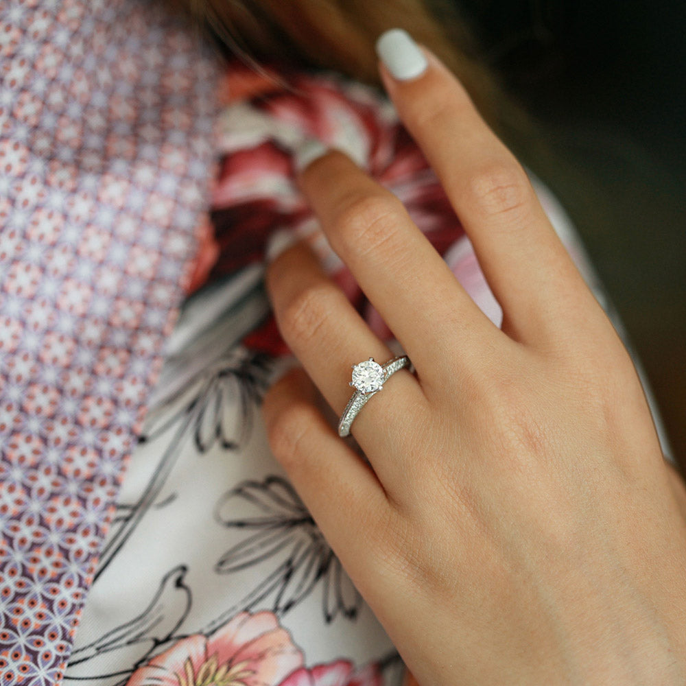 Round brilliant moissanite engagement ring on a tapered three sided pave shank in white gold