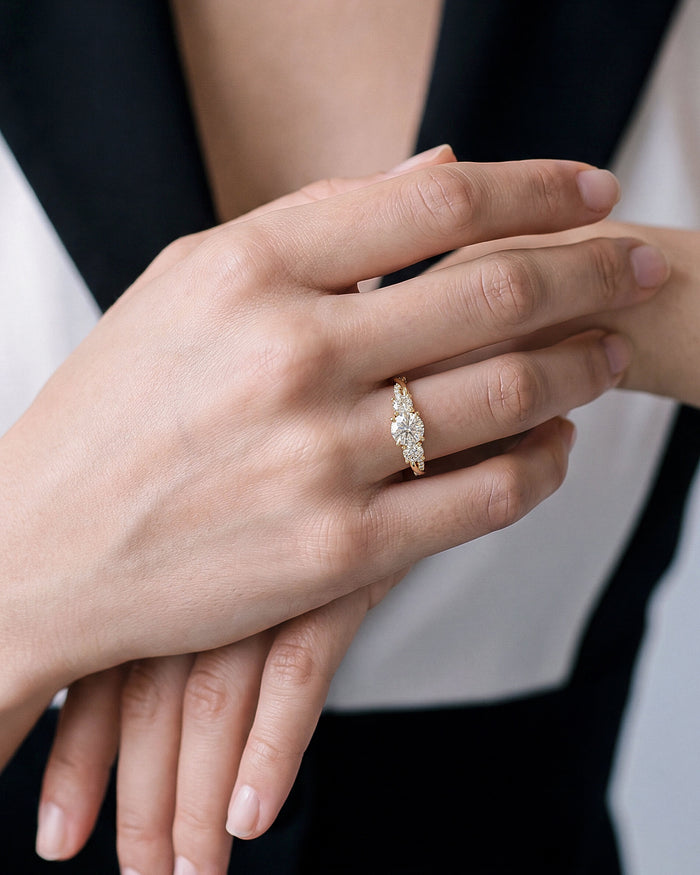 Round lab grown diamond twisted vine three stone ring in yellow gold on a hand crossed over the other