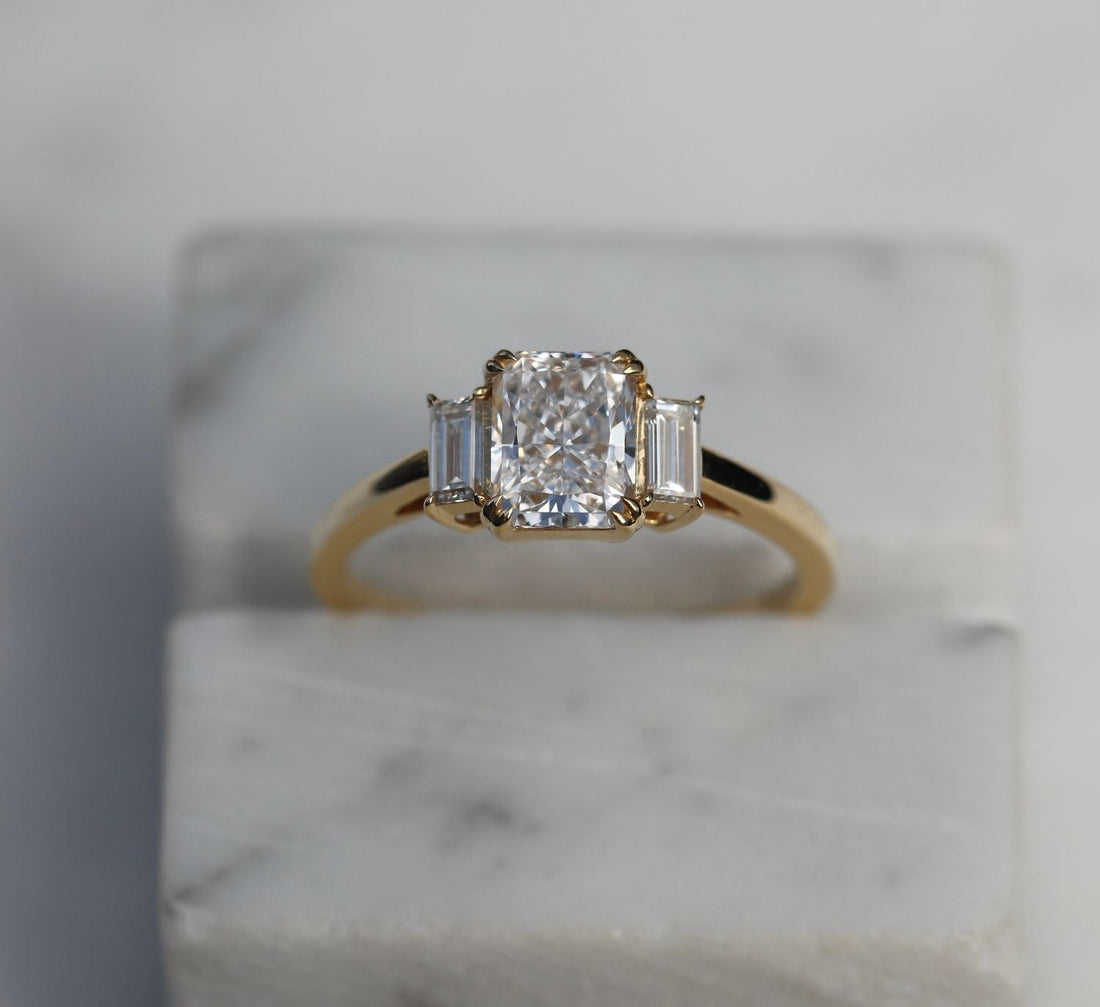 Radiant cut moissanite three stone engagement ring with upright baguette sides in yellow gold