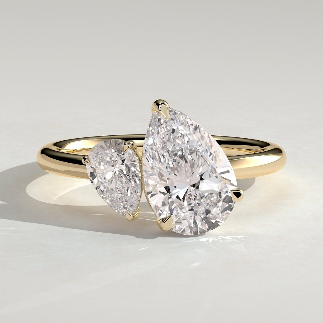 Two pear cut moissanite toi et moi engagement ring on a plain yellow gold band