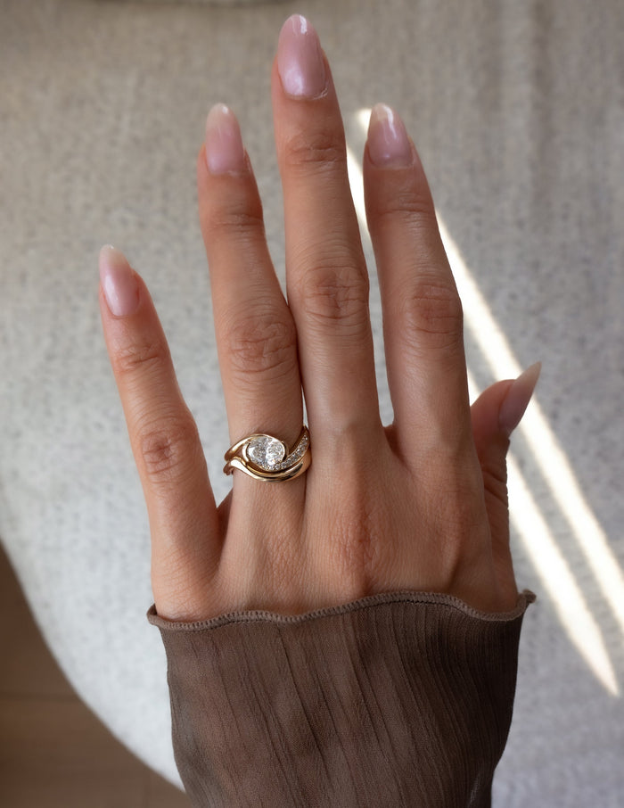 Oval lab grown diamond half pave bypass bridal set with polished wave band shown on the full hand