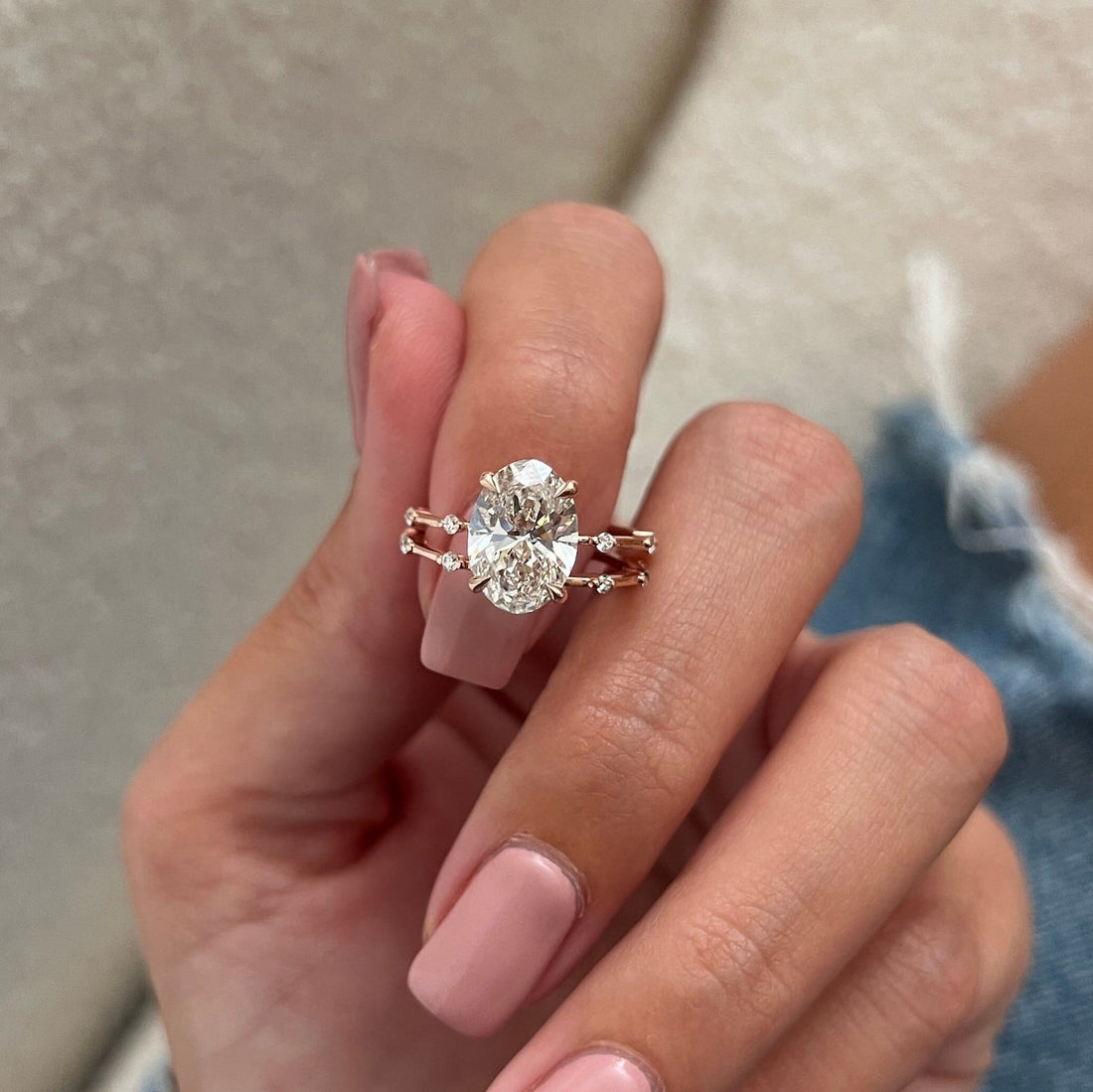 Oval moissanite dainty station bridal set in rose gold held between the fingers
