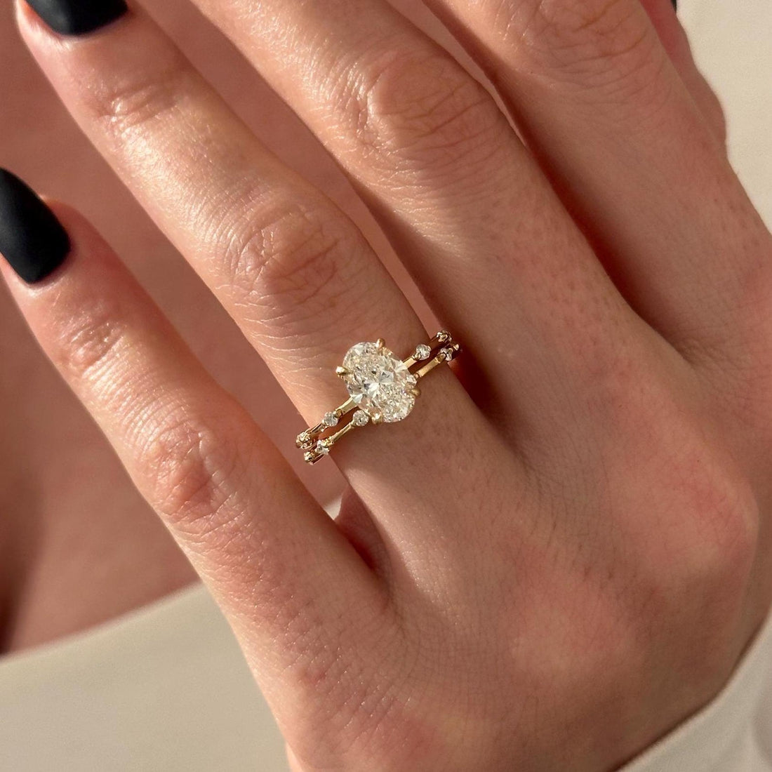 Dainty oval moissanite station bridal set in yellow gold worn on the hand