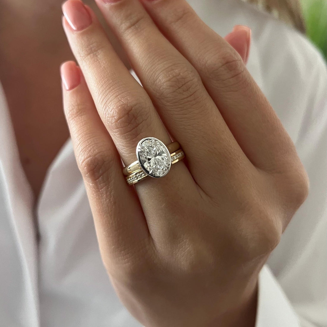 Oval moissanite bezel bridal set with channel set band worn on the hand
