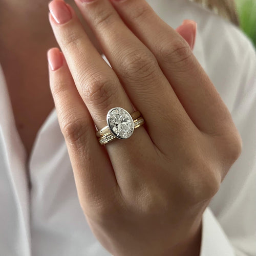 Oval moissanite bezel bridal set with channel set band worn on the hand