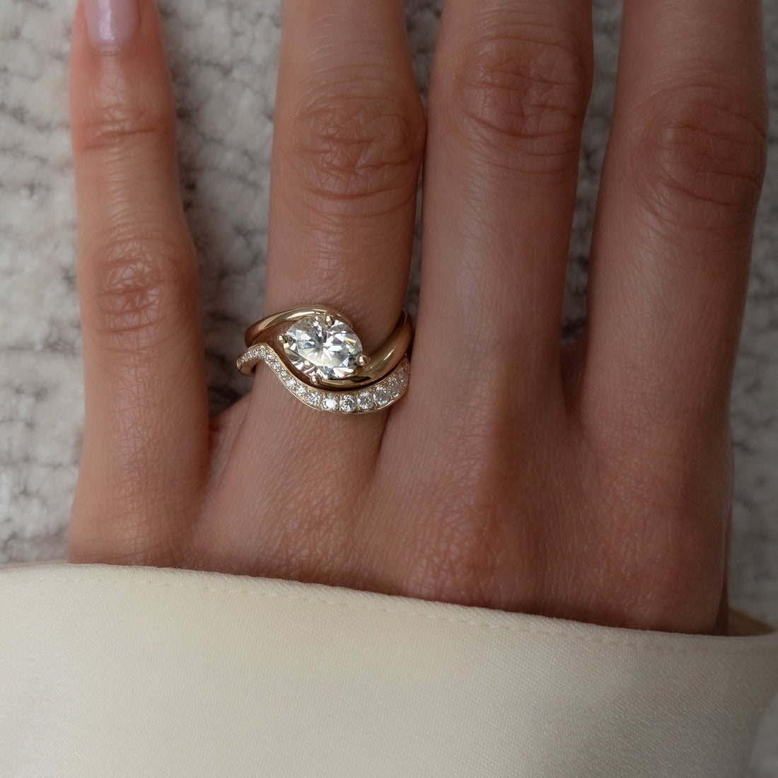 East-west oval moissanite swirl bridal set in yellow gold worn on the hand