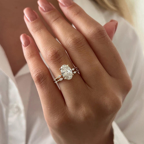 Oval moissanite bridal set with marquise station bands in yellow gold worn on the hand