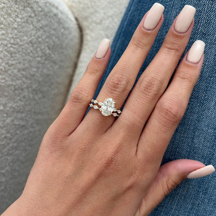 Flat hand view of oval moissanite solitaire with marquise and round stone bands