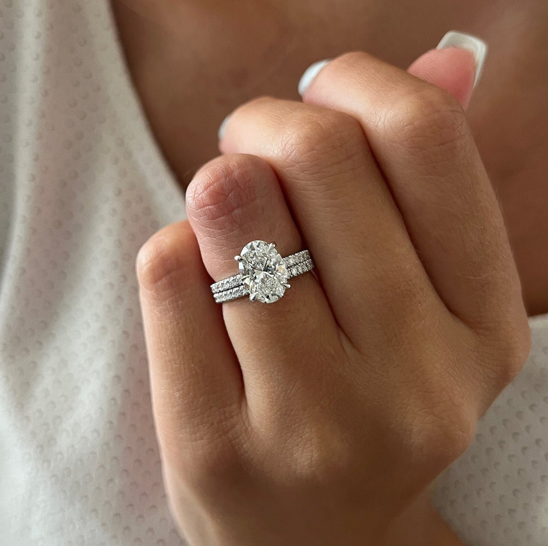 Oval moissanite hidden halo bridal set with matching pave band in white gold on the hand