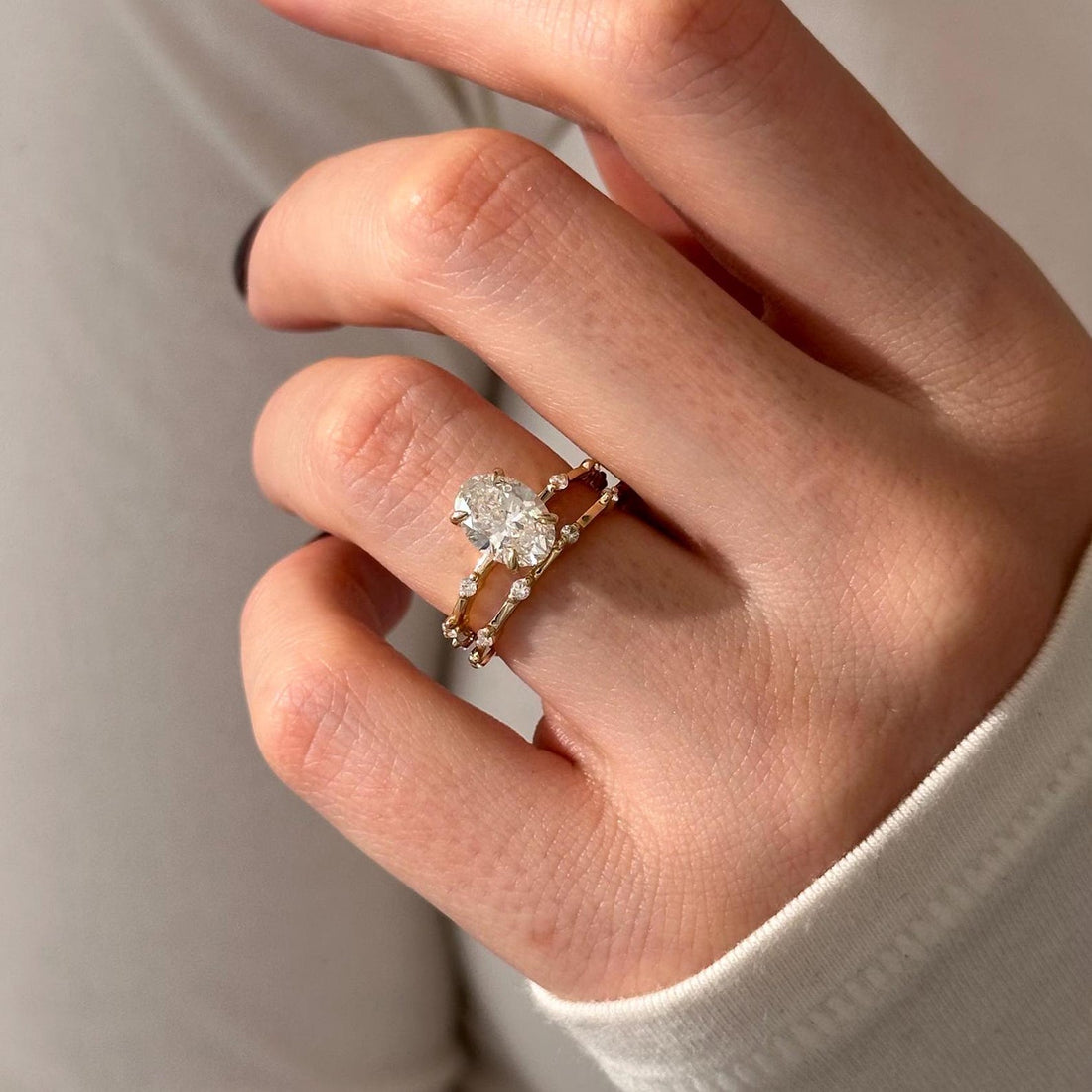 Oval moissanite station bridal set in yellow gold on the hand