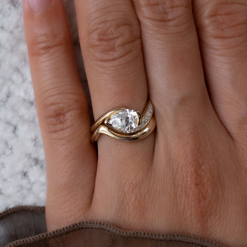 East-west pear lab grown diamond half pave swirl ring with plain wave band in yellow gold on the hand
