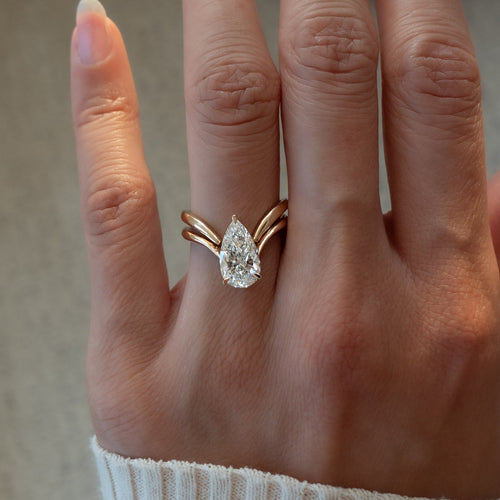 Pear moissanite V shank bridal set with plain chevron band in yellow gold on the hand