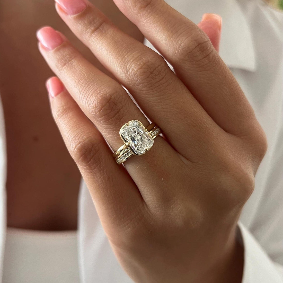Radiant moissanite claw bezel bridal set in yellow gold worn on the hand