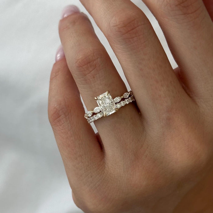 Radiant moissanite marquise station bridal set with round stone band in yellow gold on the hand