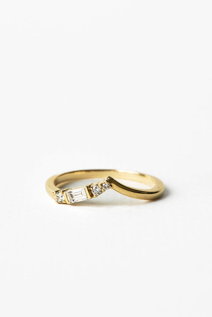 Round and baguette moissanite curved V wedding band 0.17 CT TW in yellow gold, angled view