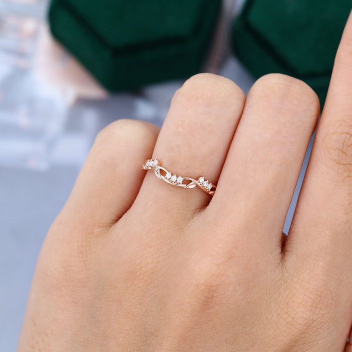 Round moissanite art deco leaf curved wedding band, worn on the finger in rose gold