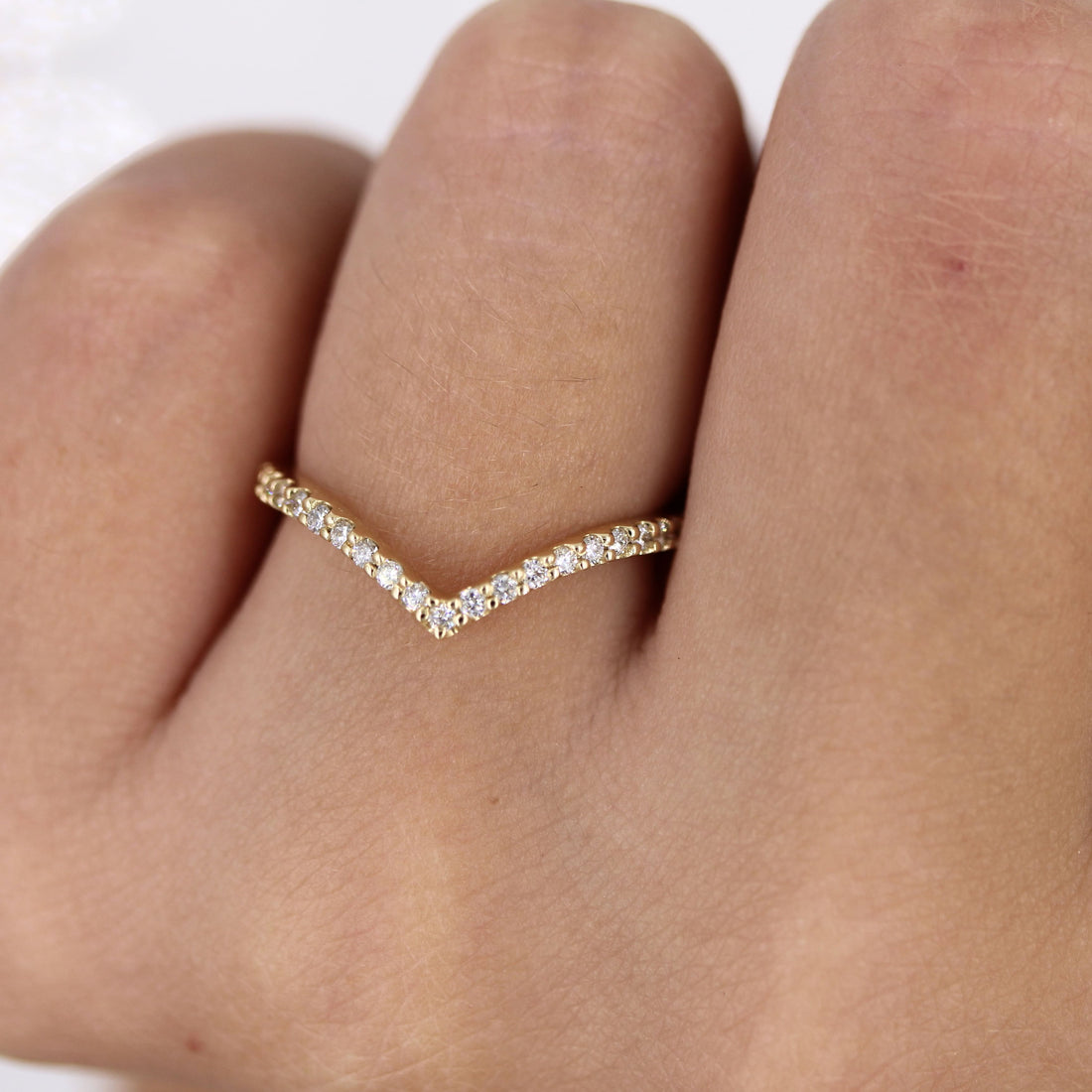 Round lab grown diamond curved V wedding band 0.17 CT TW in yellow gold on a finger