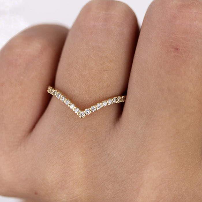 Round moissanite curved V wedding band 0.17 CT TW in yellow gold on a finger