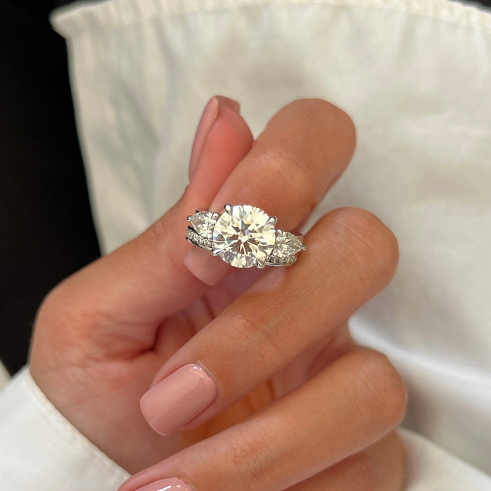 Close-up of round lab grown diamond with pear side stones and channel set wedding band